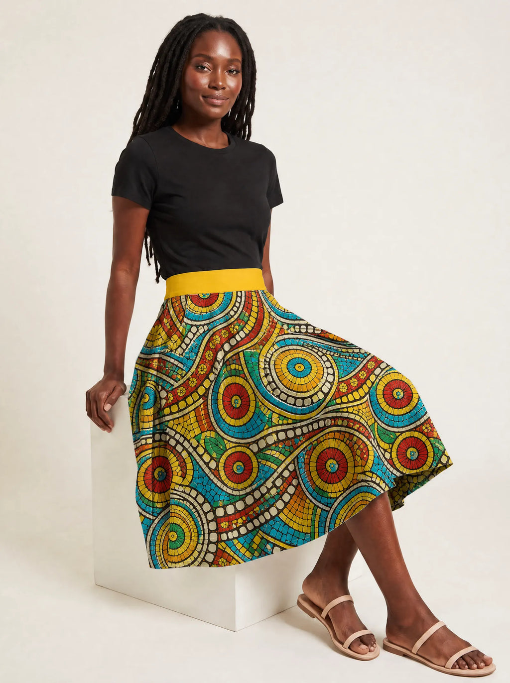 "Taji" Twirl Skirt — seated on a studio cube