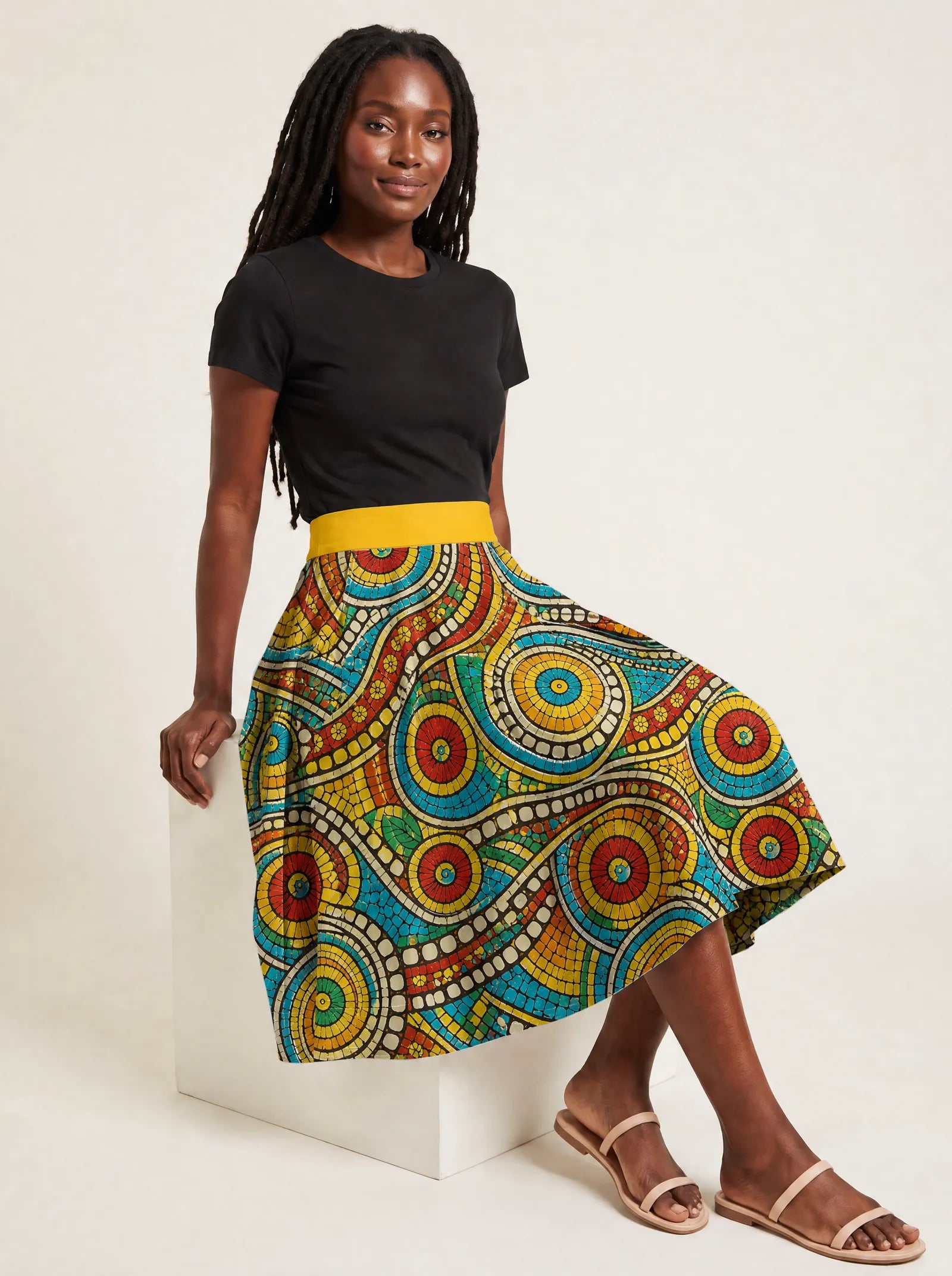 "Taji" Twirl Skirt — seated on a studio cube