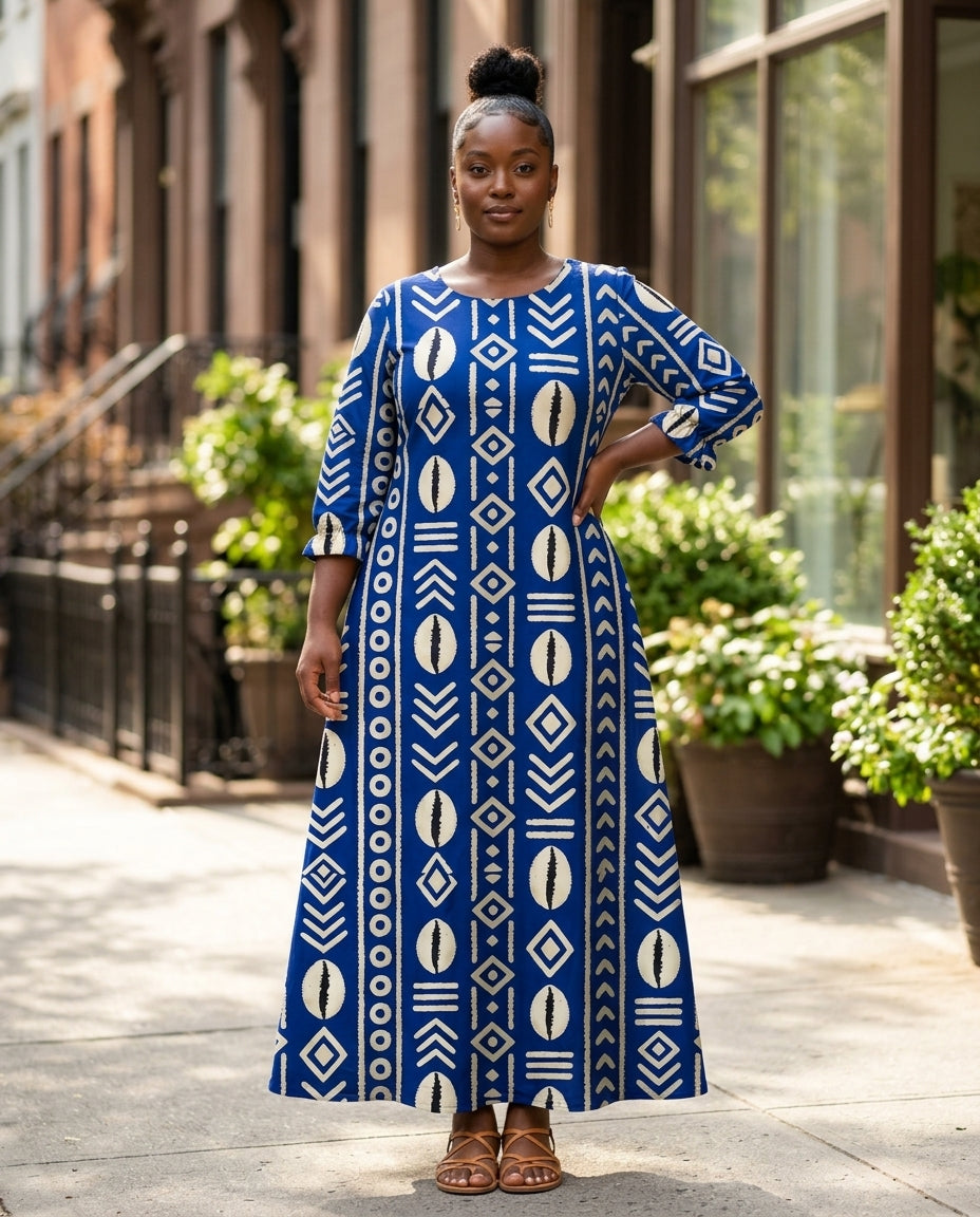 Model with a natural afro wearing the Oshun Royal Blue Maxi Dress in a royal blue and cream mudcloth print, ankle-length A-line, on a brownstone street